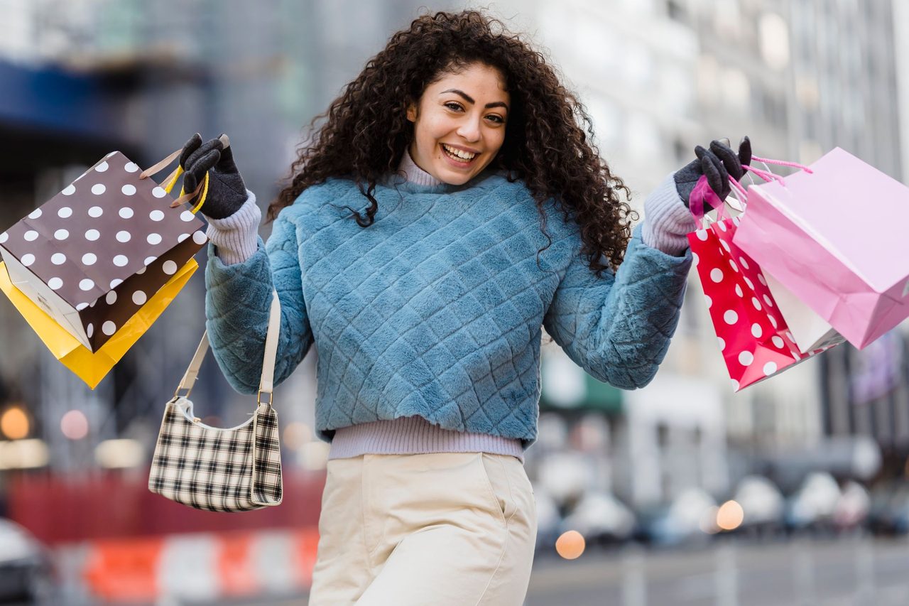 Woman laughing while carrying colourful gift bags