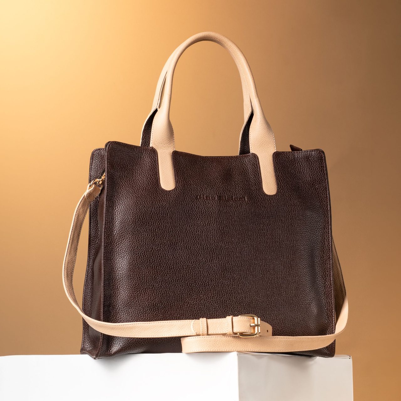 Brown leather tote bag on a yellow background